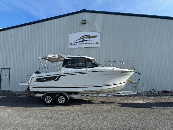 Jeanneau NC 695 2019 Jeanneau NC 695 boat on trailer outside a marine dealership.