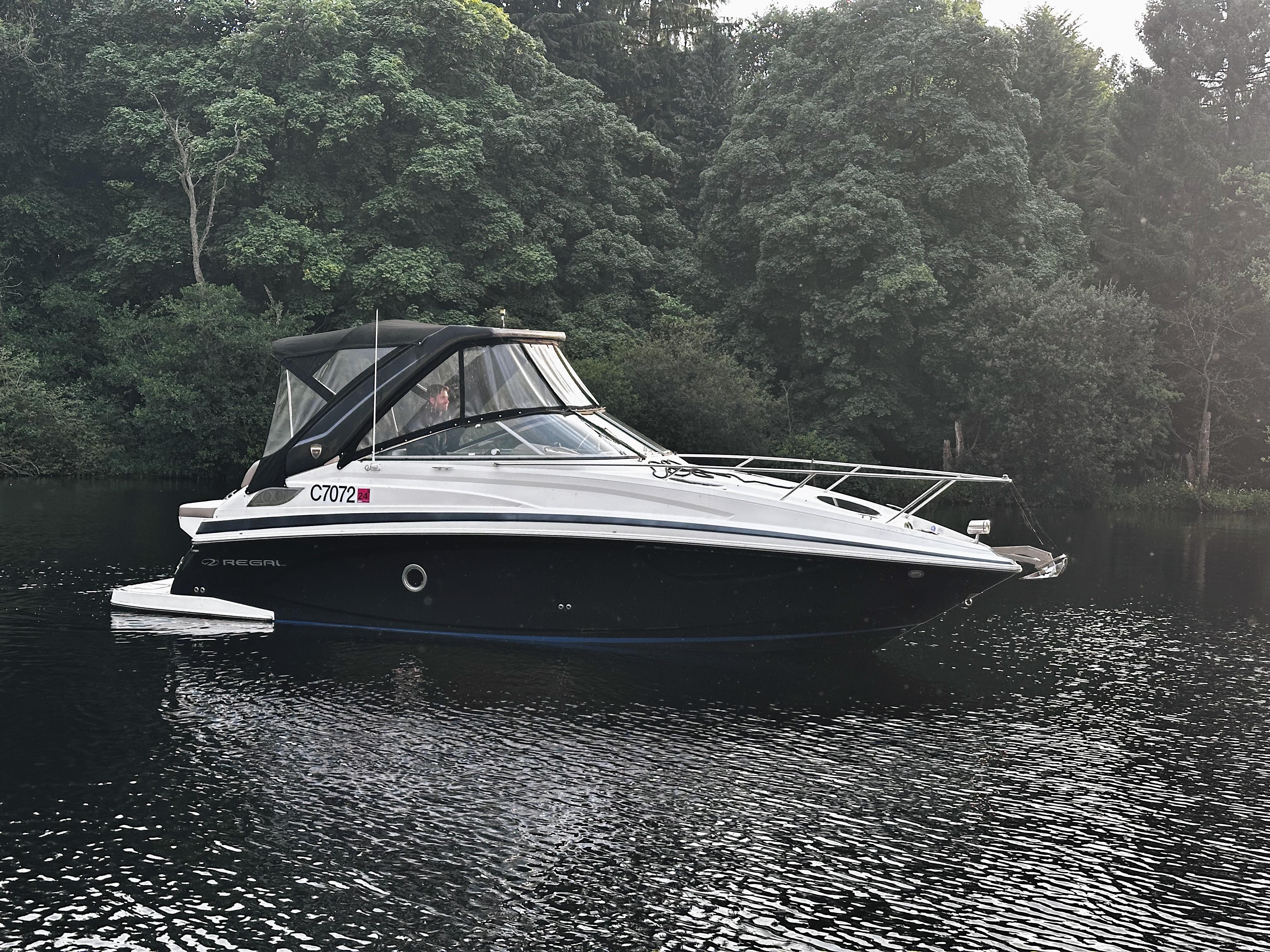 Regal 28 Express 2018 Regal 28 Express boat on a calm lake, surrounded by lush greenery.