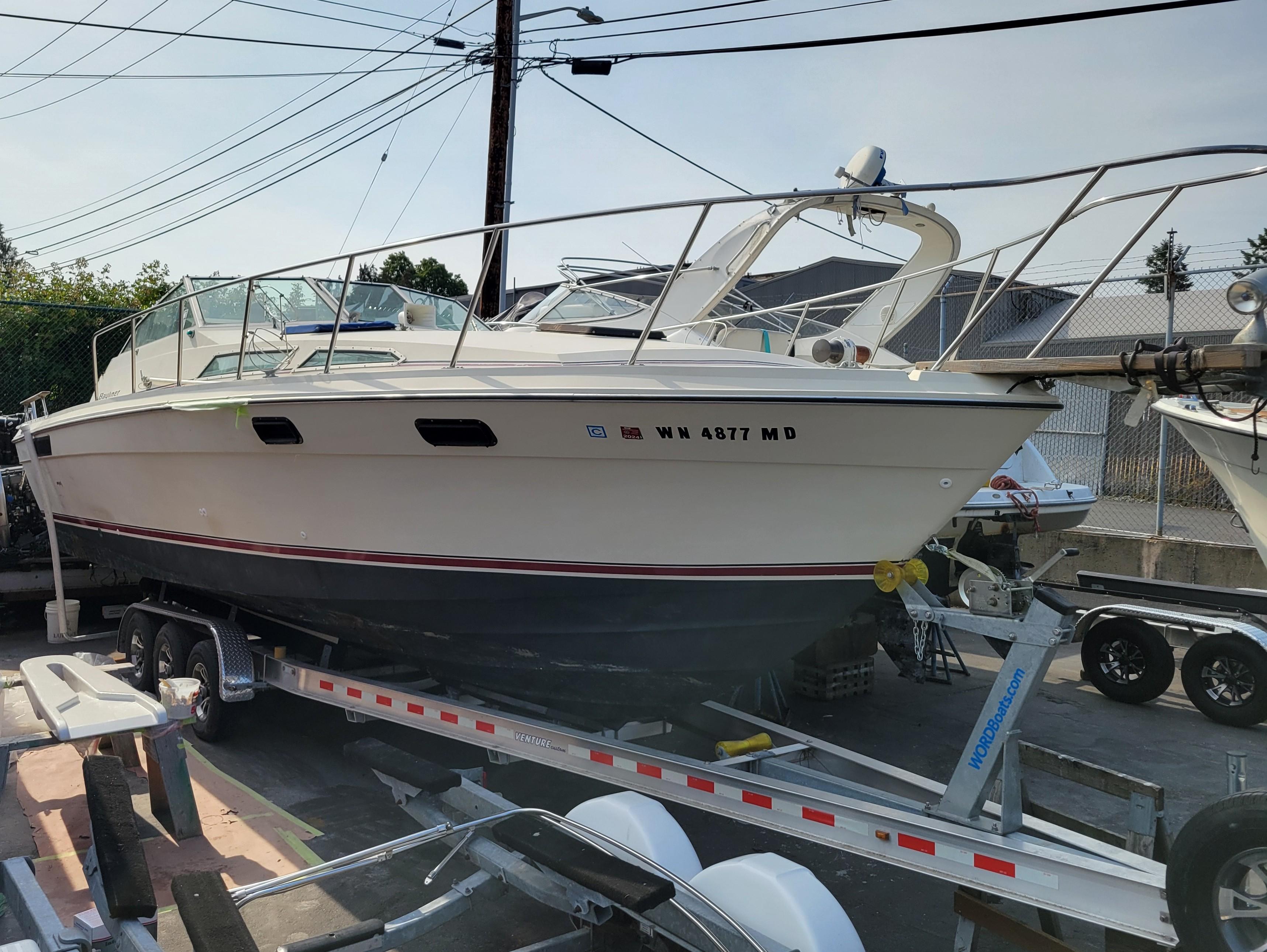 Bayliner 3250 1979 Bayliner 3250 boat on trailer, parked outdoors, side view.