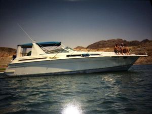 Four Winns Express Cruiser 1992 Four Winns Express Cruiser on water with passengers, mountainous background.