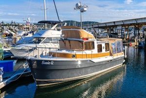 Ranger Tugs R-31 CB 2015 Ranger Tugs R-31 CB boat docked in marina, featuring tan canopy and sleek design.