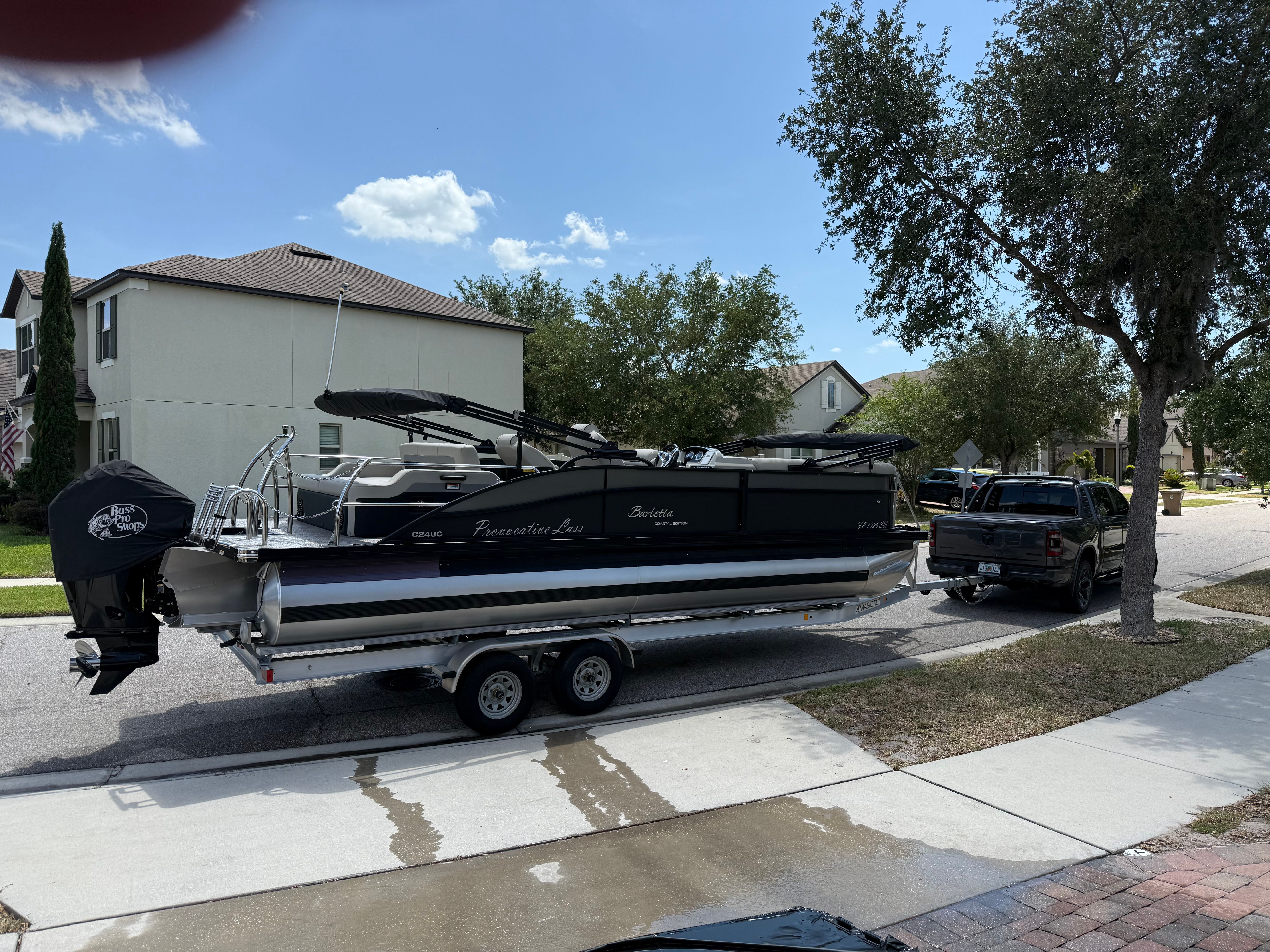 Barletta C24UC 2021 Barletta C24UC pontoon boat on trailer, parked in suburban neighborhood.