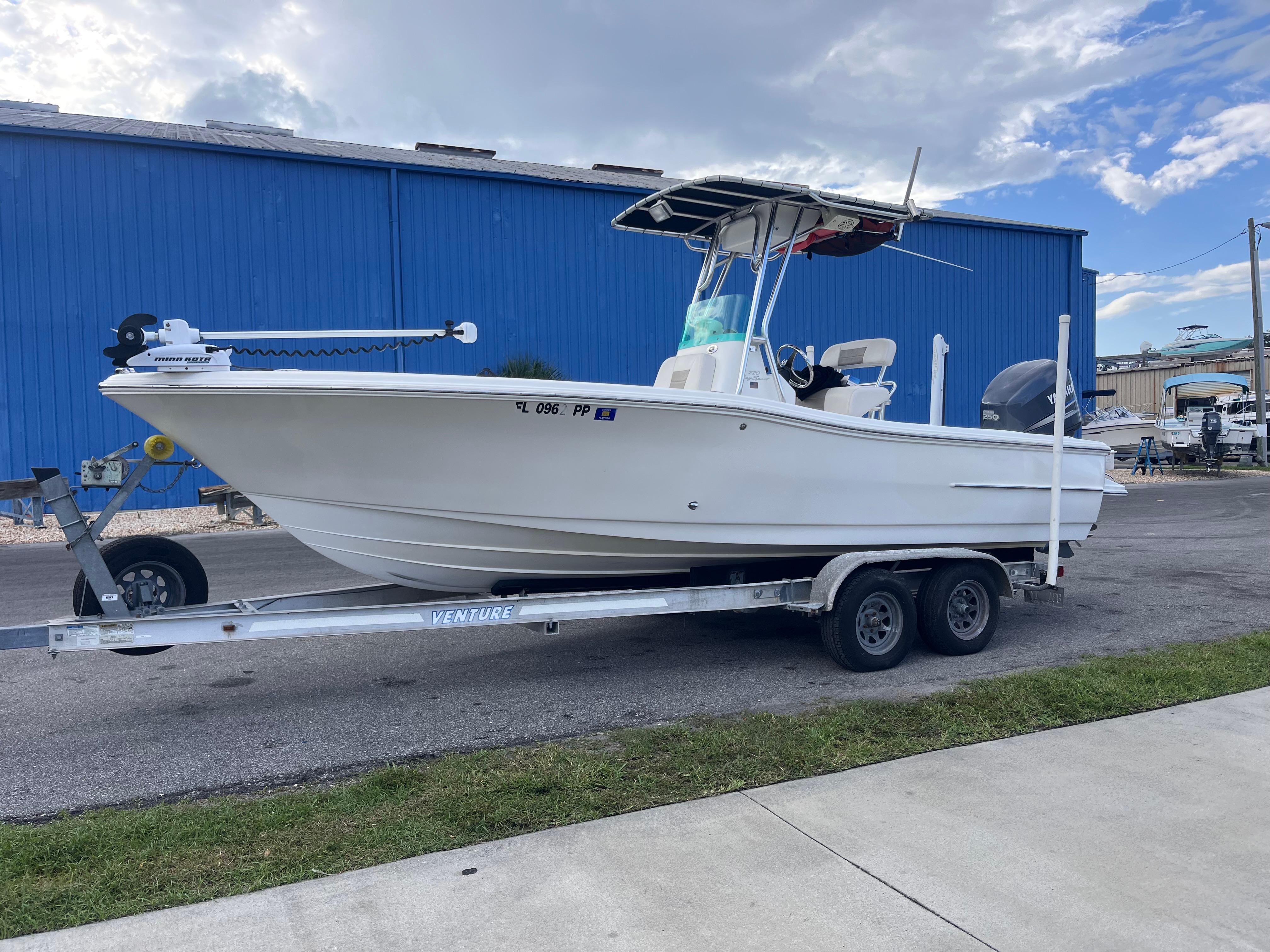 Pioneer 220 Bay Sport 2009 Pioneer 220 Bay Sport boat on trailer, parked near blue building under cloudy sky.