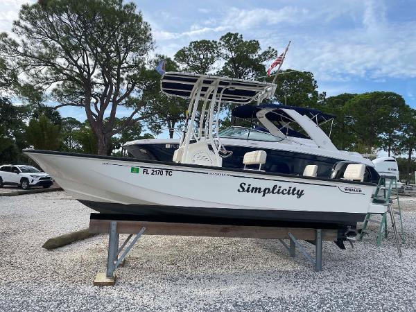 Boston Whaler 190 Montauk 2022 Boston Whaler 190 Montauk boat named "Simplicity" on a stand, surrounded by trees.