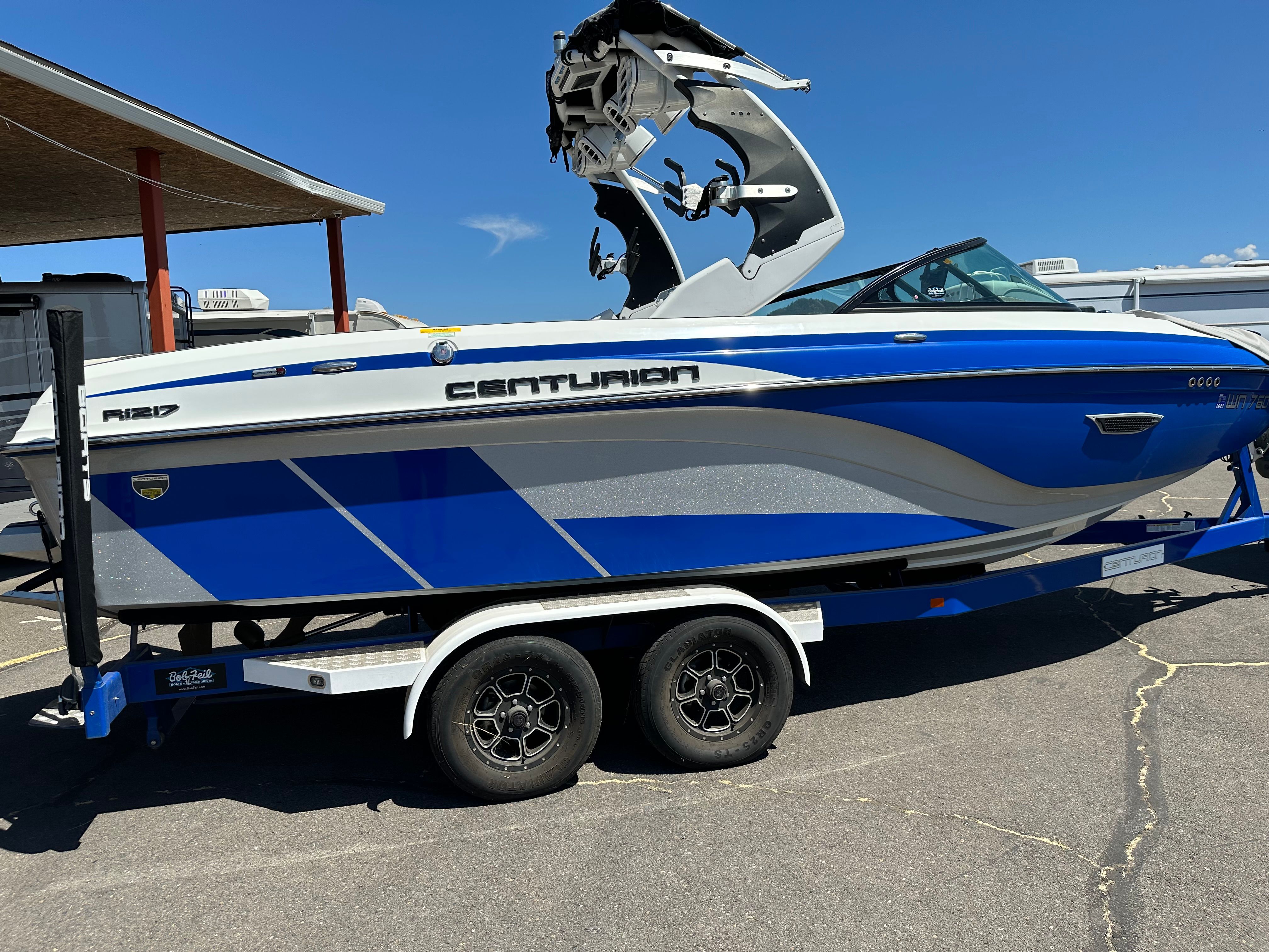 Centurion Ri217 2017 Centurion Ri217 boat in blue and white on a trailer, parked outdoors.
