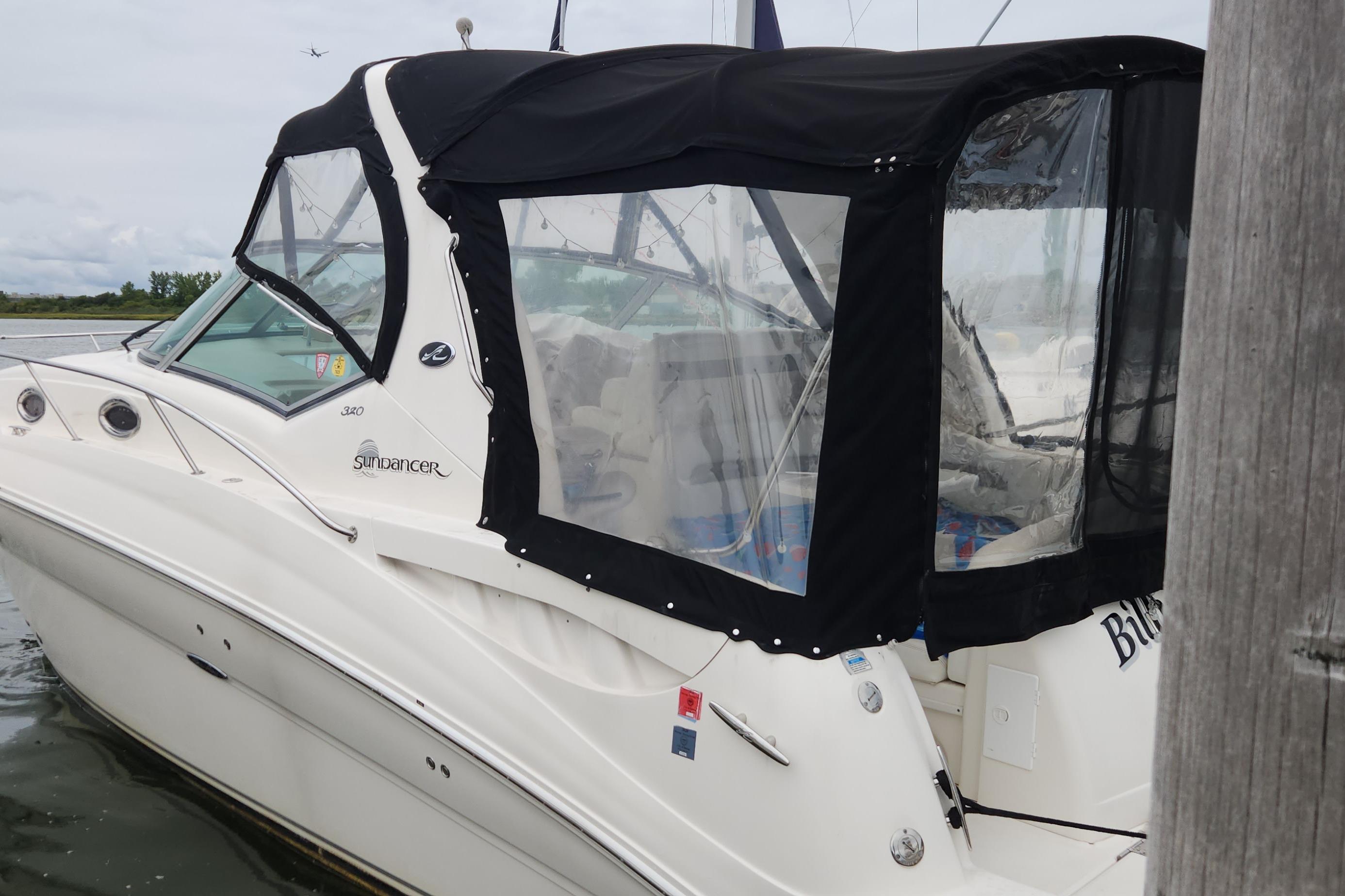 Sea Ray 320 Sundancer 2005 Sea Ray 320 Sundancer boat with black canopy docked in calm waters.