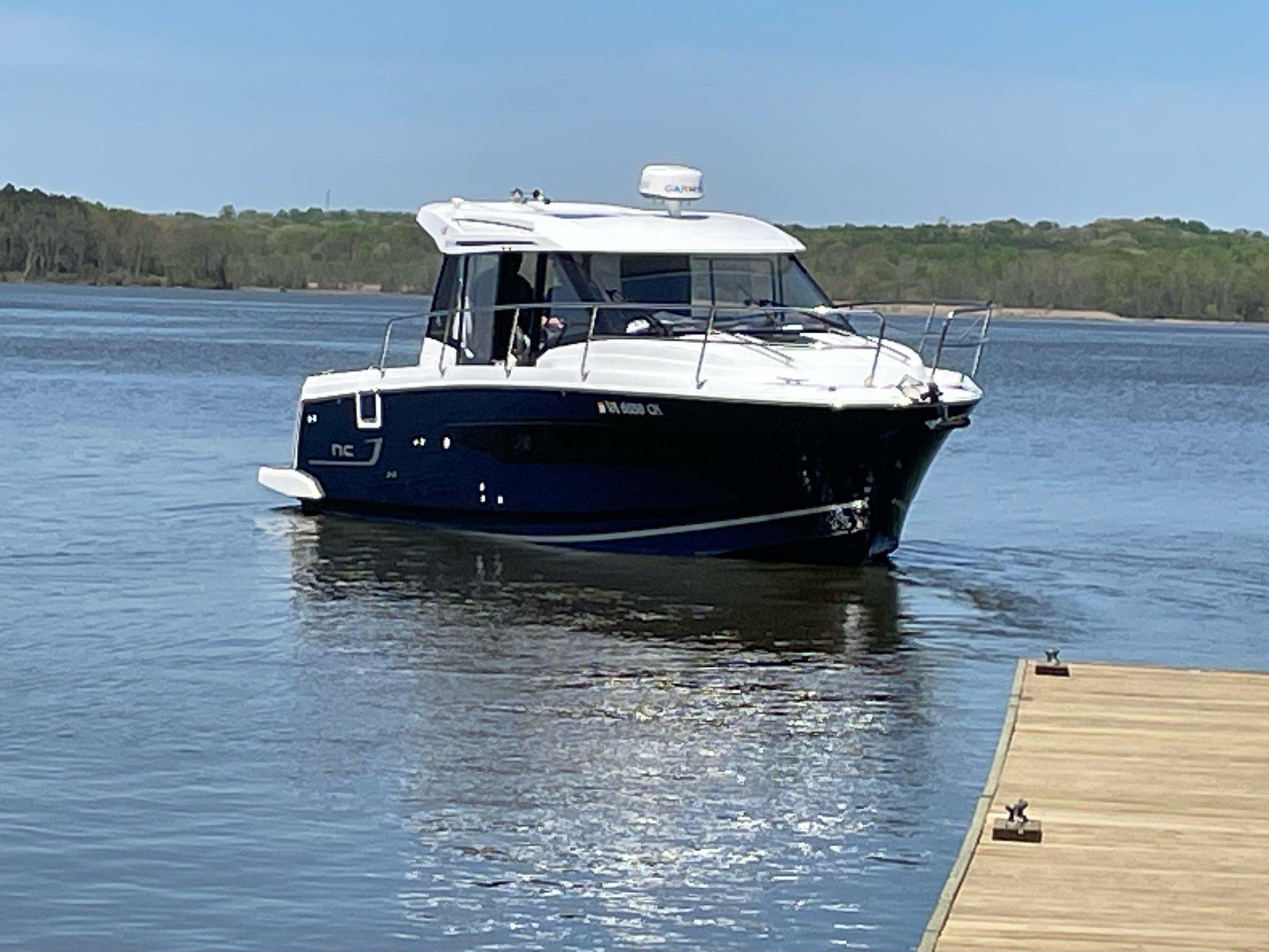 Jeanneau NC 895 2020 Jeanneau NC 895 boat on calm water near a wooden dock.