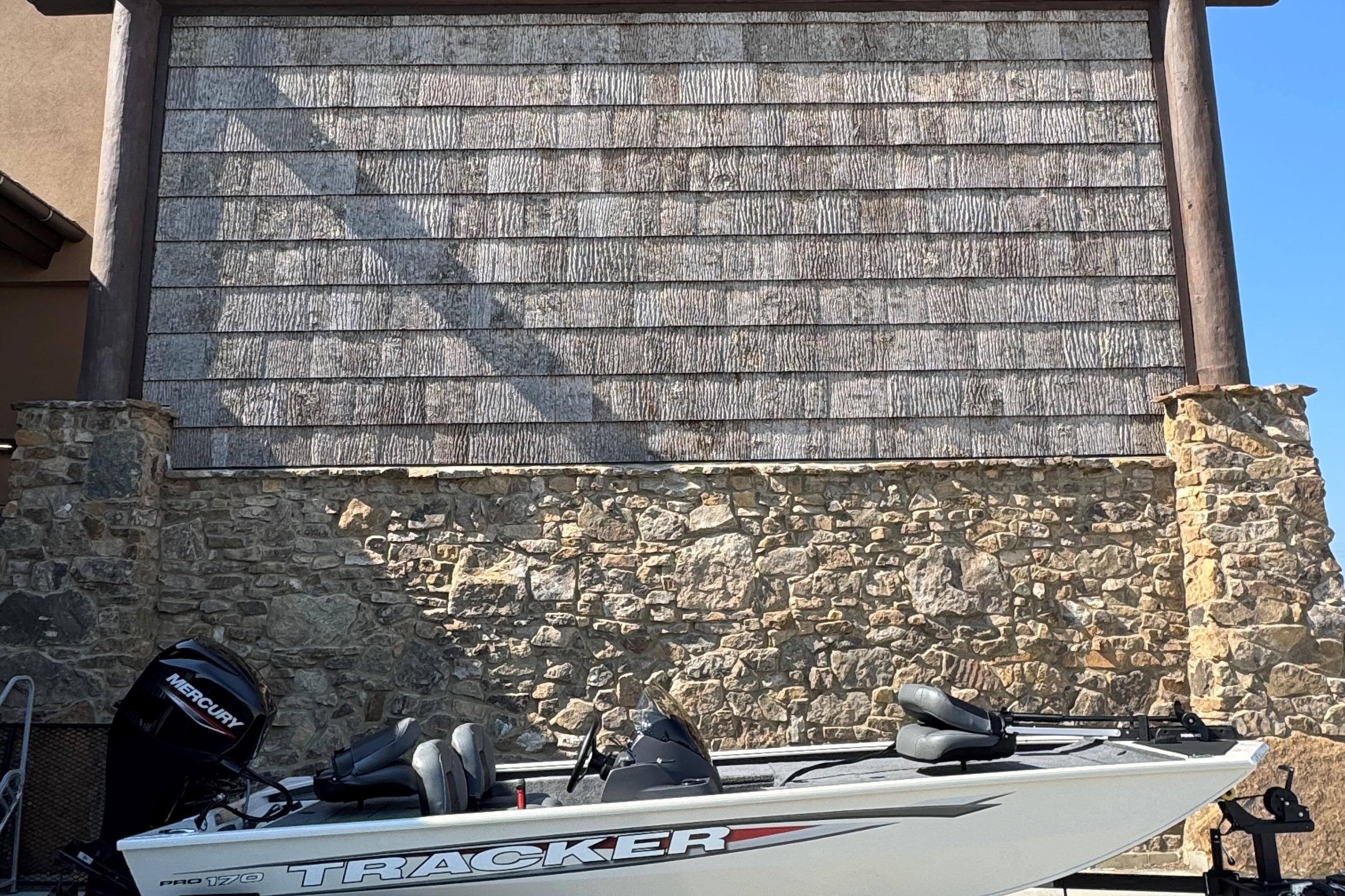 Tracker Pro 170 2026 Tracker Pro 170 boat parked against a rustic stone wall.