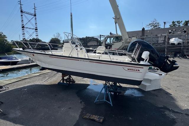 Boston Whaler 190 Montauk 2017 Boston Whaler 190 Montauk boat on stands, dockside, with Mercury outboard motor.