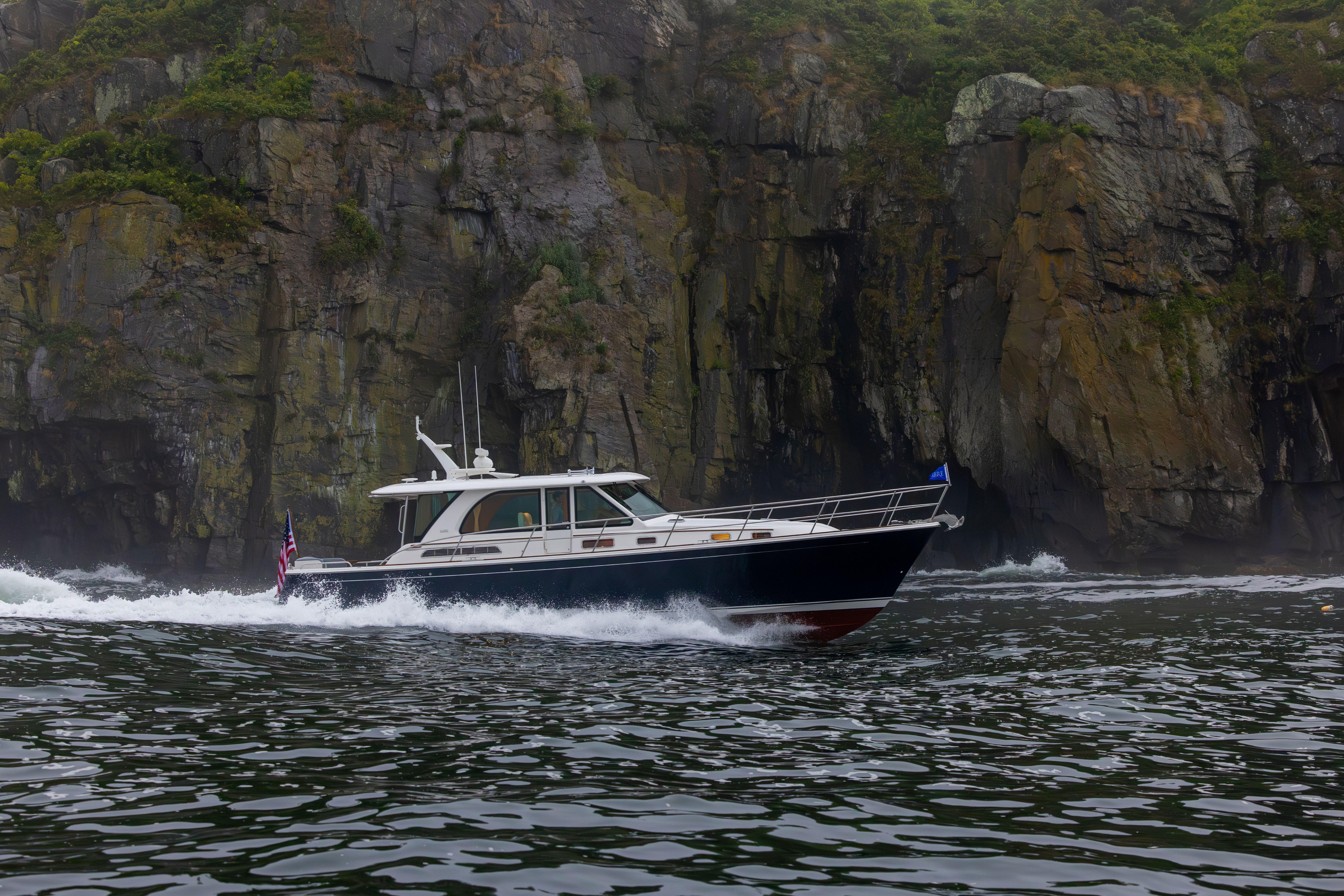 Sabre 45 Salon Express 2026 Sabre 45 Salon Express cruising near rocky cliffs in scenic waters.