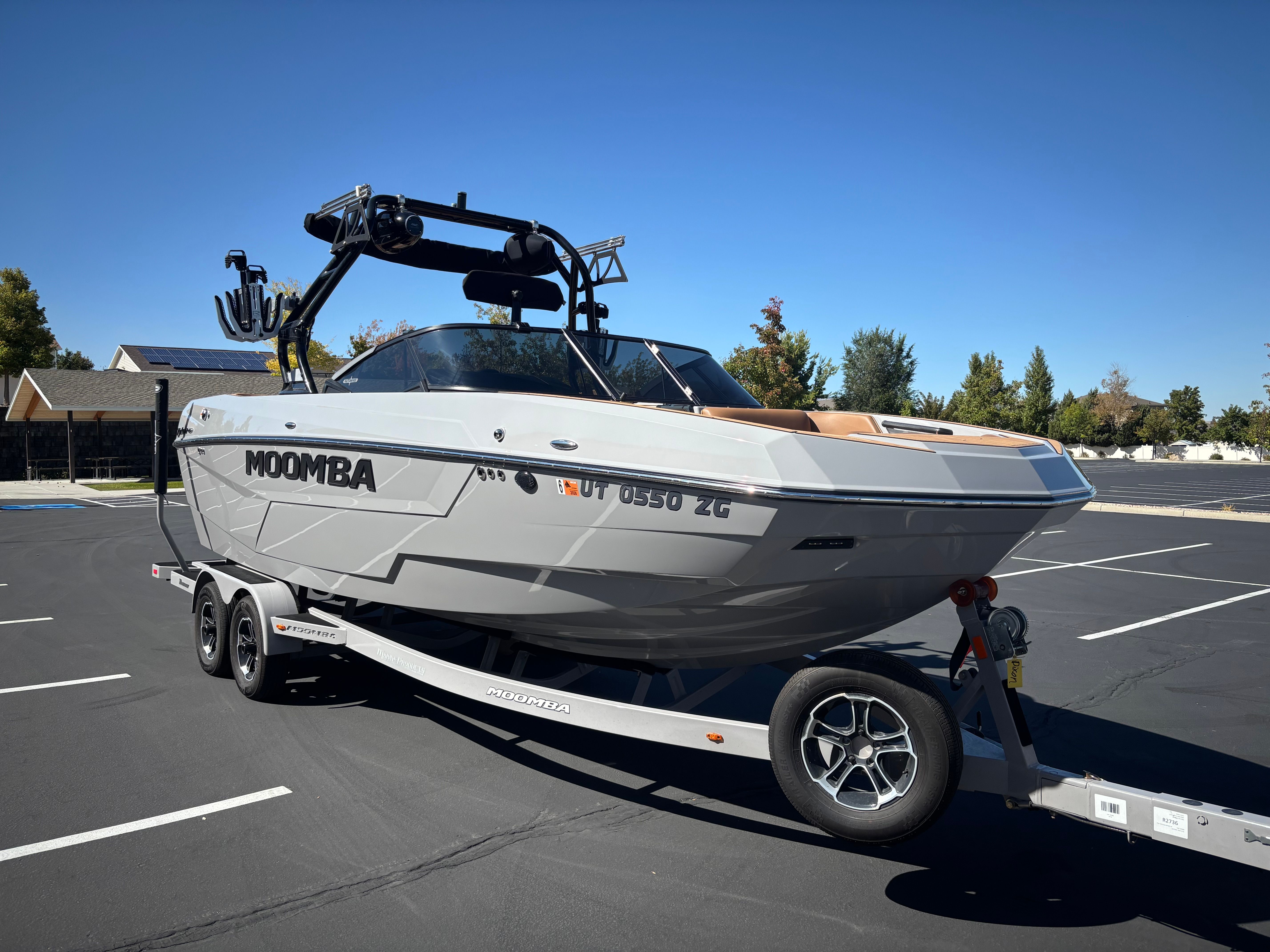 Moomba Tykon 2024 Moomba Tykon boat on trailer in parking lot, clear sky background.