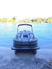 Sylvan L3 DLZ 2023 Sylvan L3 DLZ pontoon boat docked on a sandy shore with scenic water view.