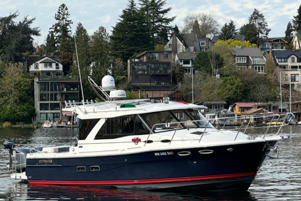 Cutwater C-302 Coupe 2017 Cutwater C-302 Coupe boat on a scenic waterfront with houses and trees.