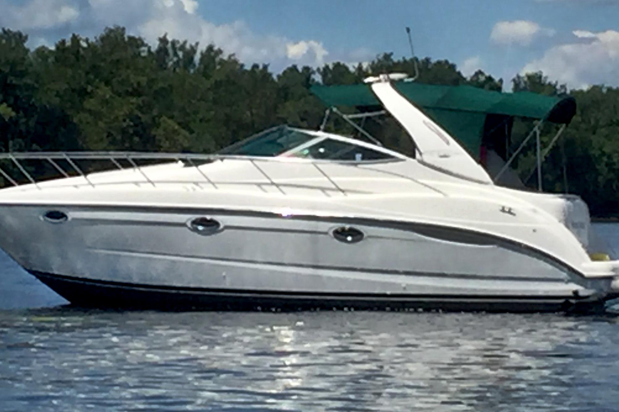 Maxum 3500 SCR 2001 Maxum 3500 SCR boat on calm water with green canopy, trees in background.