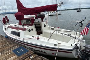 Sonic 23 1983 Sonic 23 sailboat docked, featuring maroon sails and American flag.