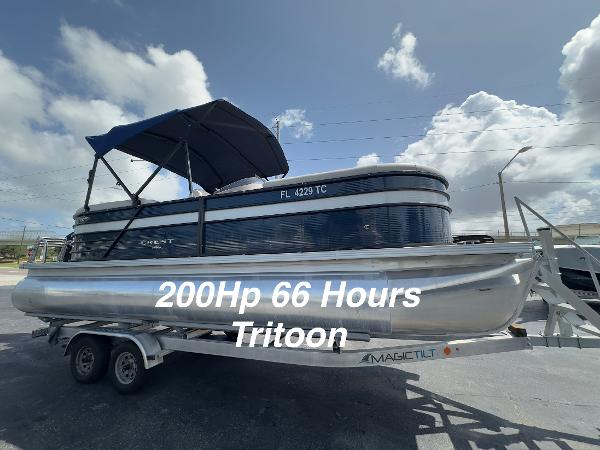 Crest Classic DLX 220 2022 Crest Classic DLX 220 Tritoon on trailer, 200HP, 66 hours, under blue sky.
