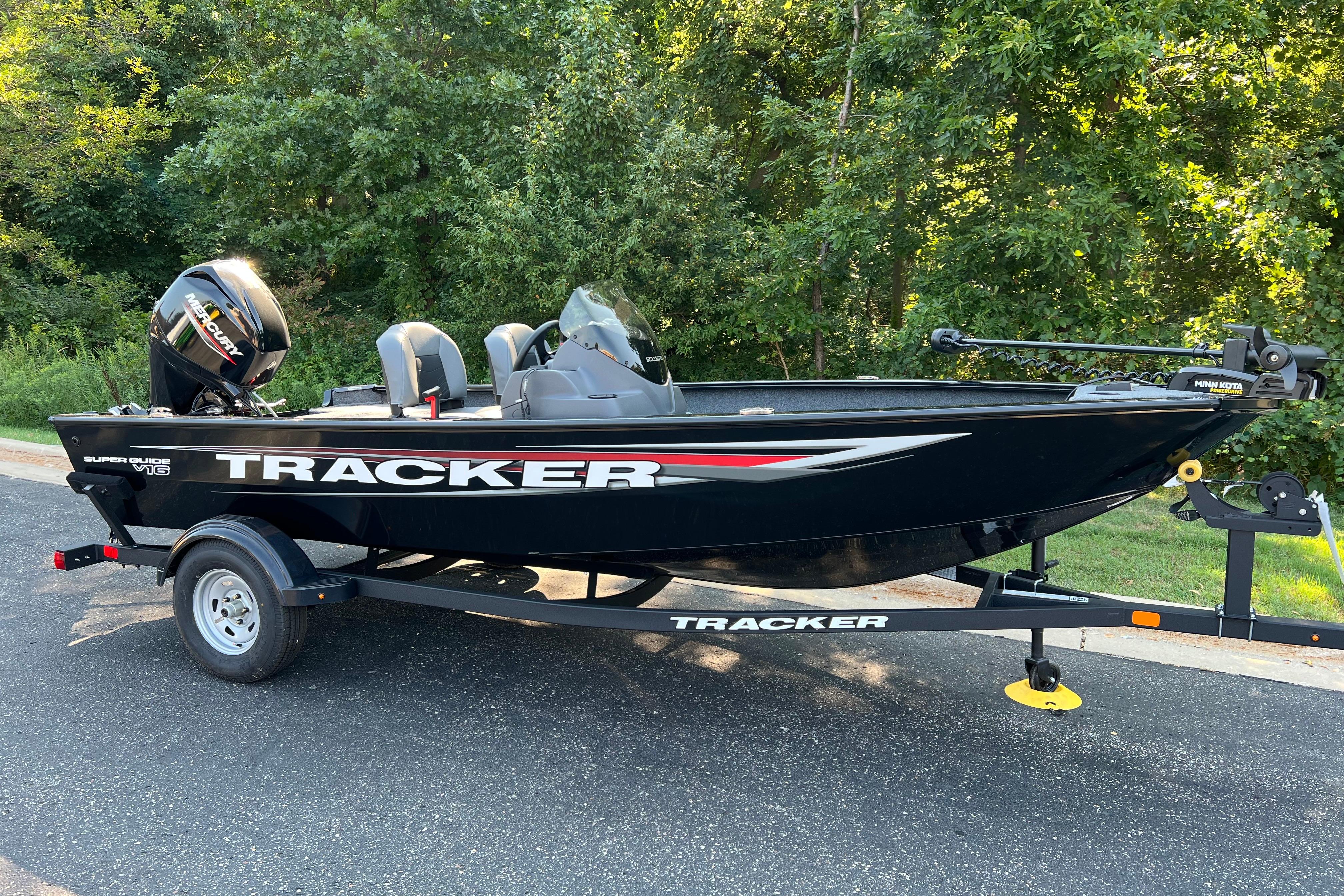 Tracker Super Guide V-16 SC 2026 Tracker Super Guide V-16 SC boat on trailer, parked near lush greenery.
