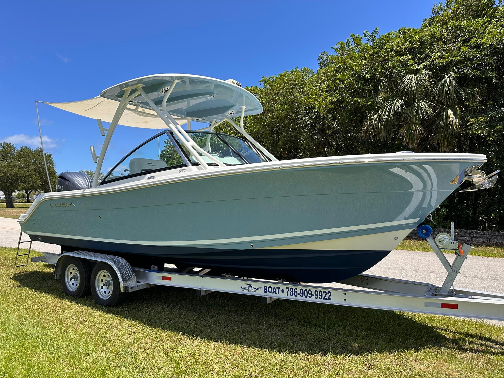 Cobia 240 Dual Console 2022 Cobia 240 Dual Console boat on trailer, parked on grass under clear blue sky.
