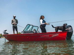 Lund 1650 Angler 2026 Lund 1650 Angler boat with two people and a dog fishing on a lake.