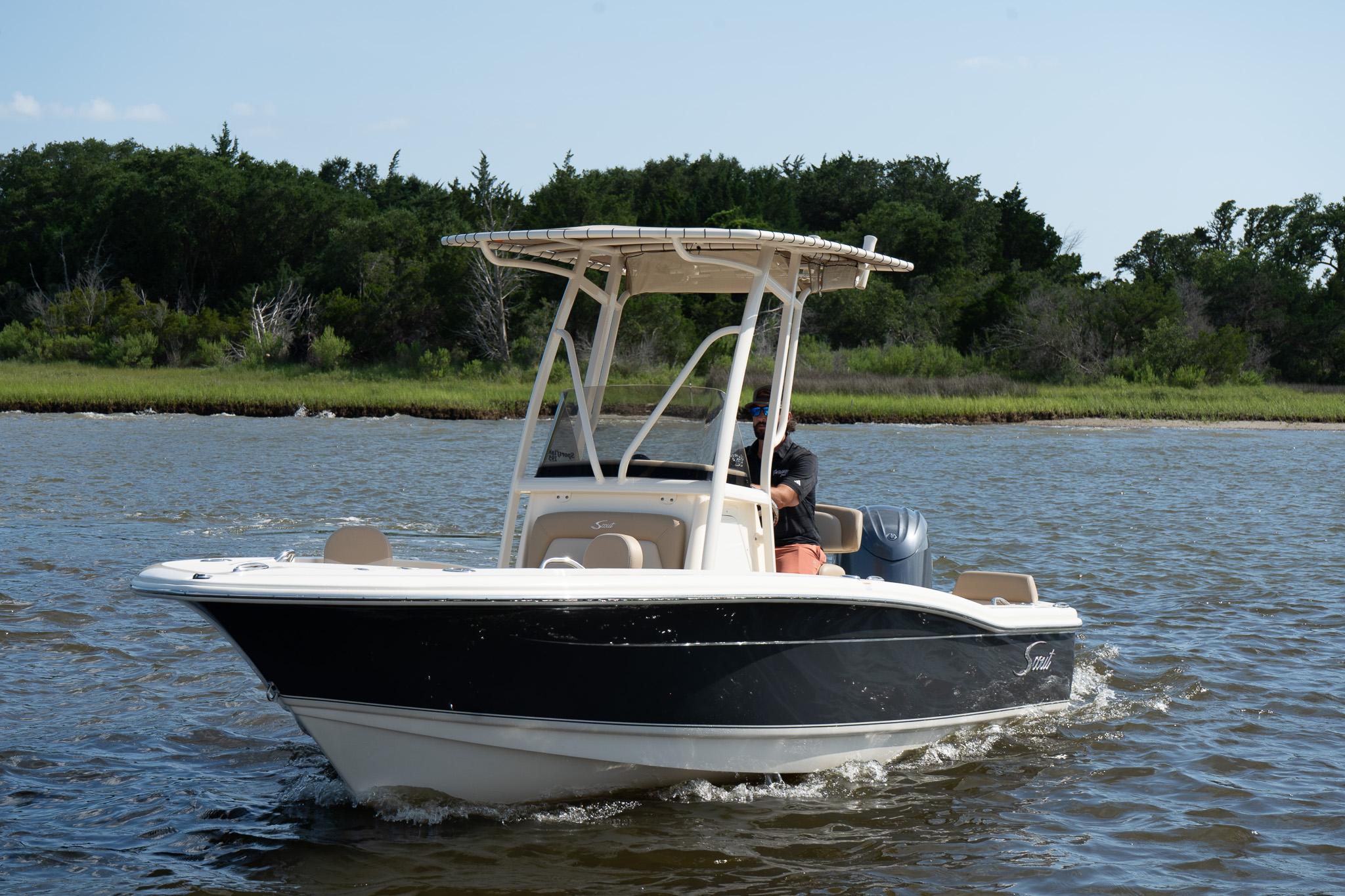 Scout 195 Sportfish 2025 Scout 195 Sportfish boat cruising on a calm river with lush green shoreline.