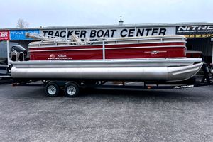 Sun Tracker Party Barge 24 DLX 2025 Sun Tracker Party Barge 24 DLX pontoon boat on trailer at dealership.
