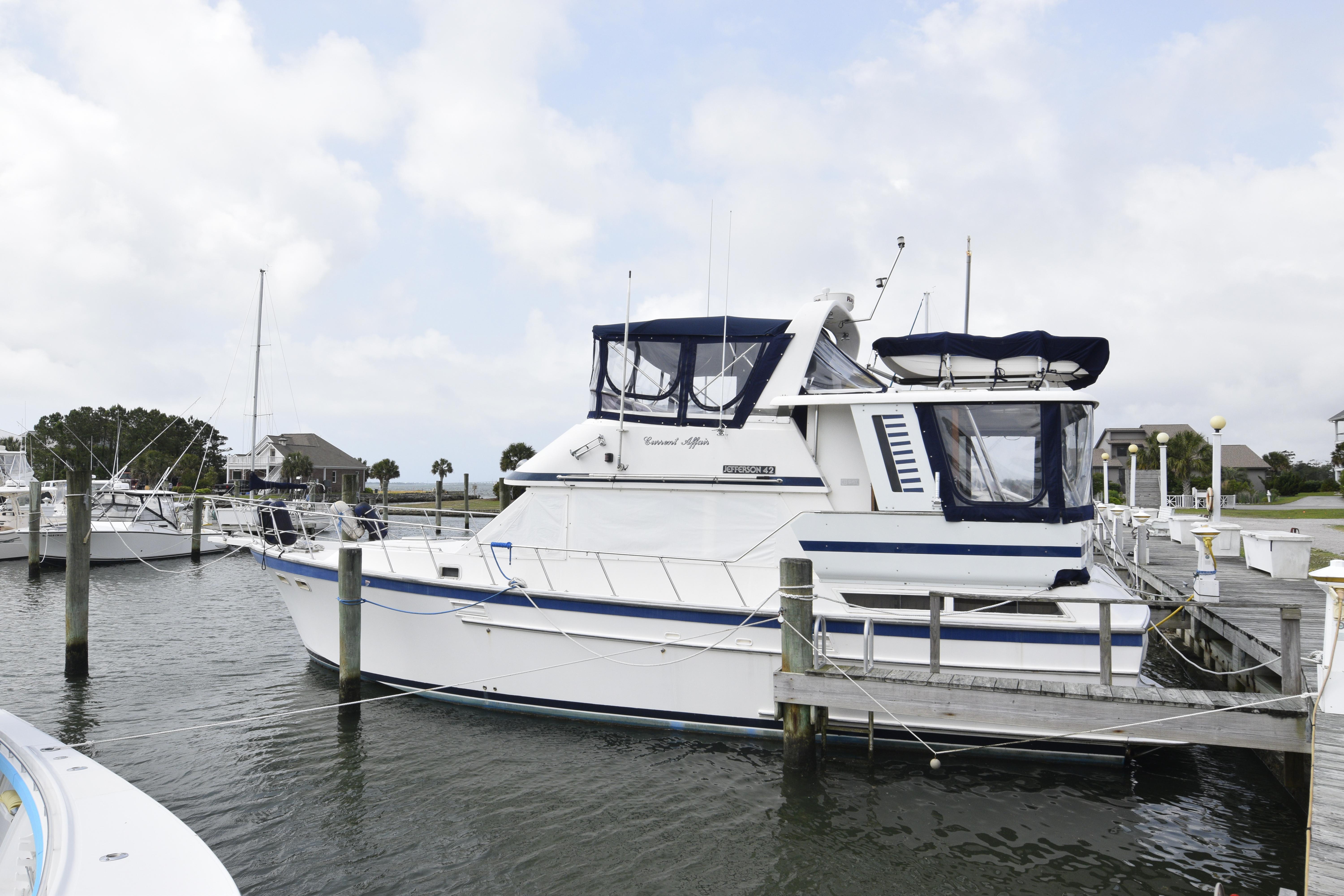 Jefferson Sundeck 1987 Jefferson Sundeck yacht docked at a marina on a cloudy day.