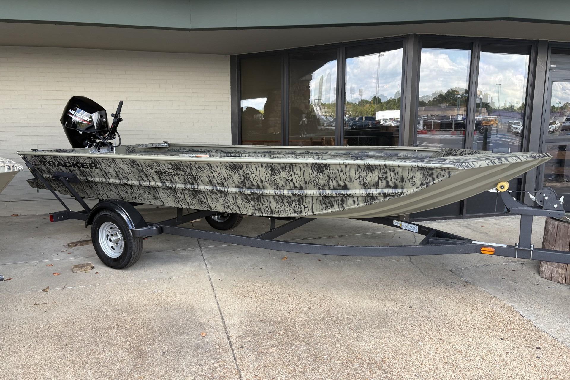 Tracker Grizzly 1654 T Sportsman 2026 Tracker Grizzly 1654 T Sportsman boat on trailer, camo design, parked outside a building.