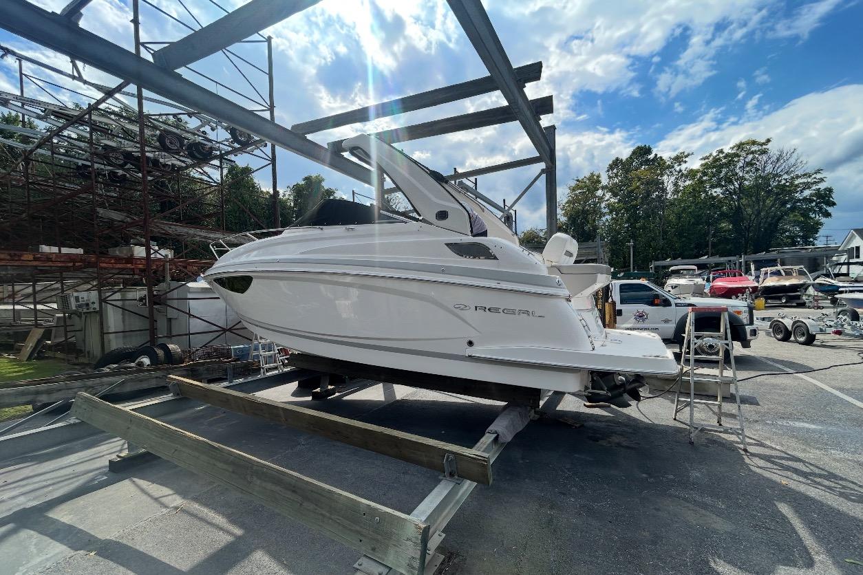 Regal 28 Express 2019 Regal 28 Express boat on a trailer in a marina setting under a blue sky.