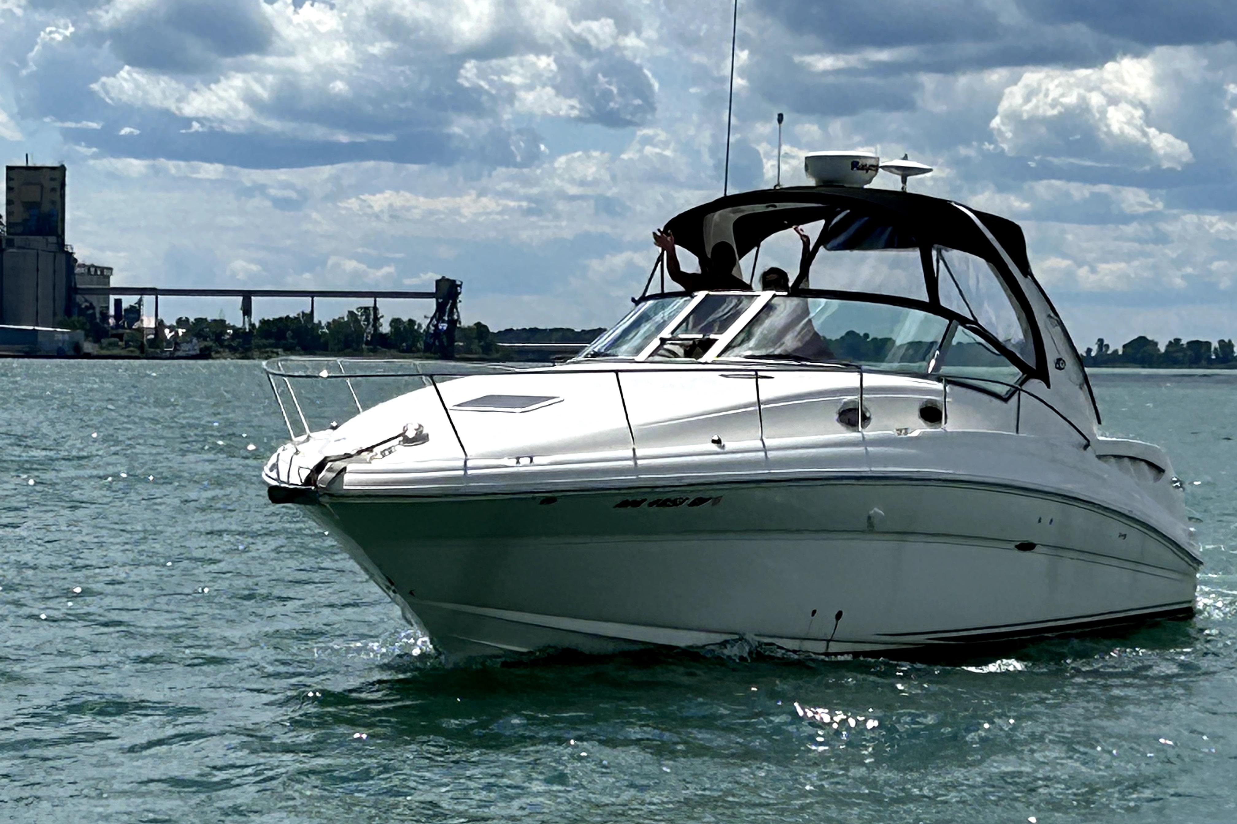 Sea Ray 320 Sundancer 2005 Sea Ray 320 Sundancer cruising on a sunny day with industrial backdrop.