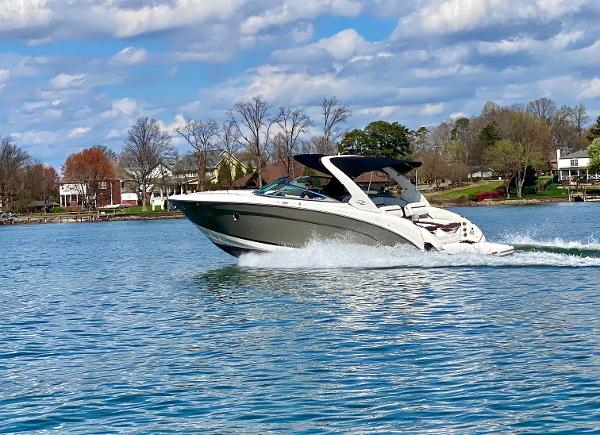 Regal 3200 Bowrider 2016 Regal 3200 Bowrider cruising on a scenic lake under a partly cloudy sky.