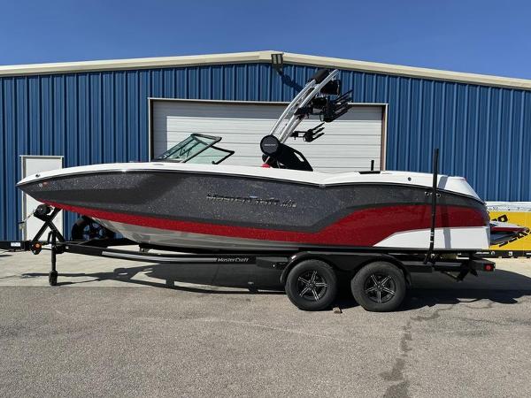 MasterCraft NXT 22 2024 MasterCraft NXT 22 boat on trailer in front of blue building.