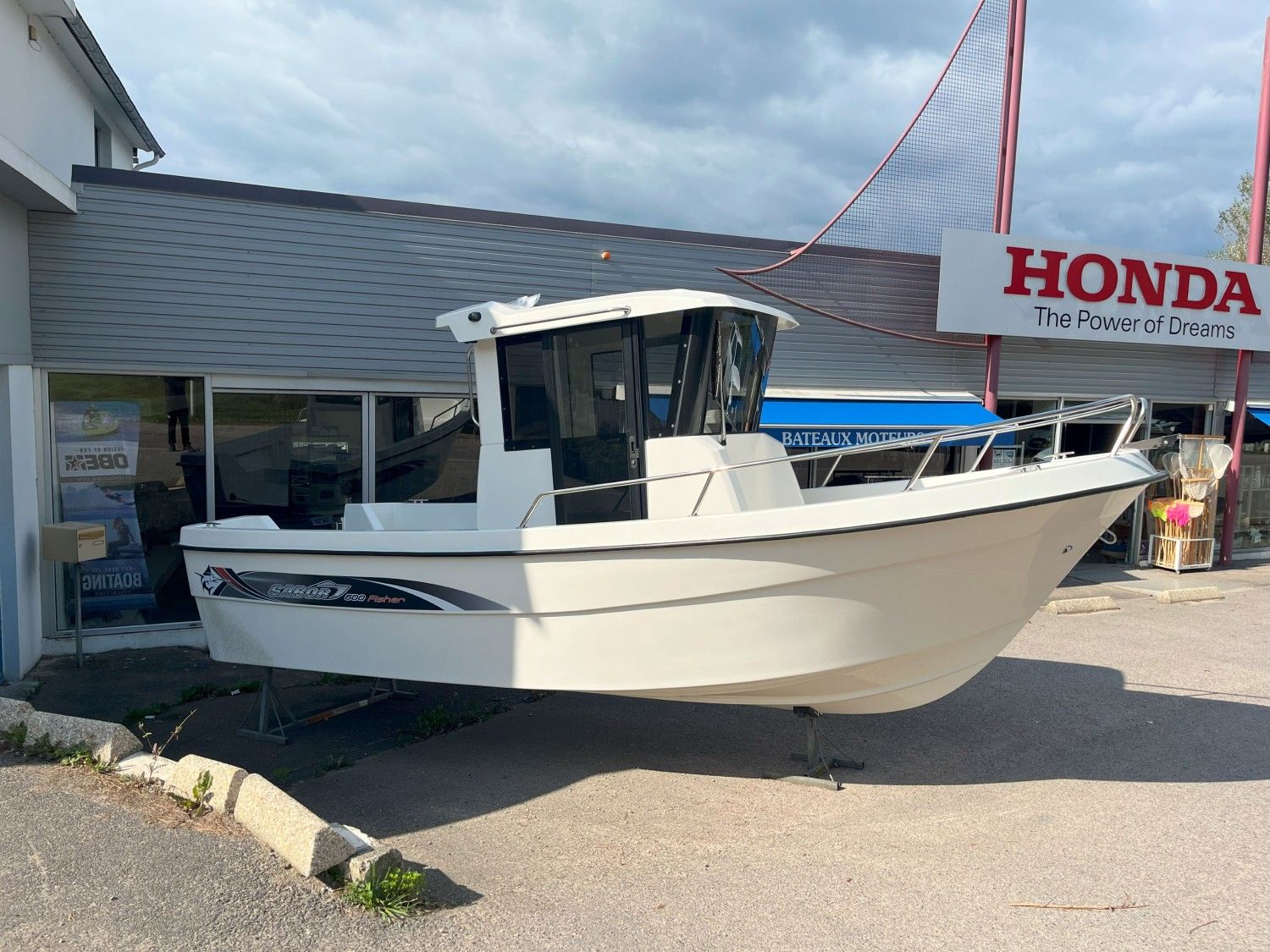 Sabor 600 cabin 2025 Sabor 600 Cabin boat displayed outside a dealership under a Honda sign.