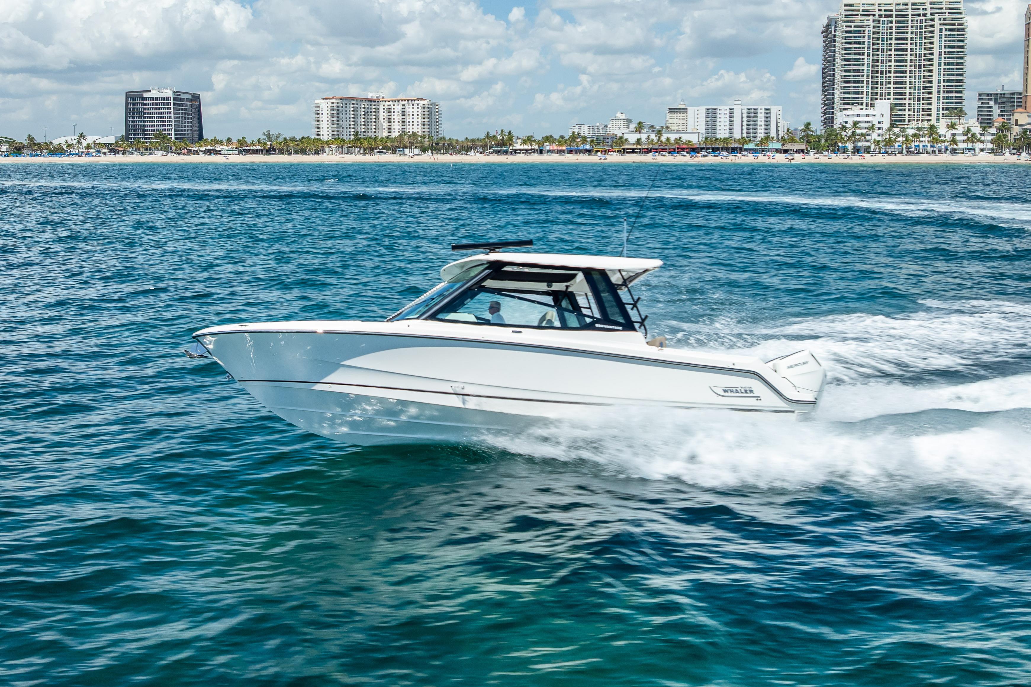 Boston Whaler 330 Vantage 2025 Boston Whaler 330 Vantage cruising on blue ocean near city skyline.