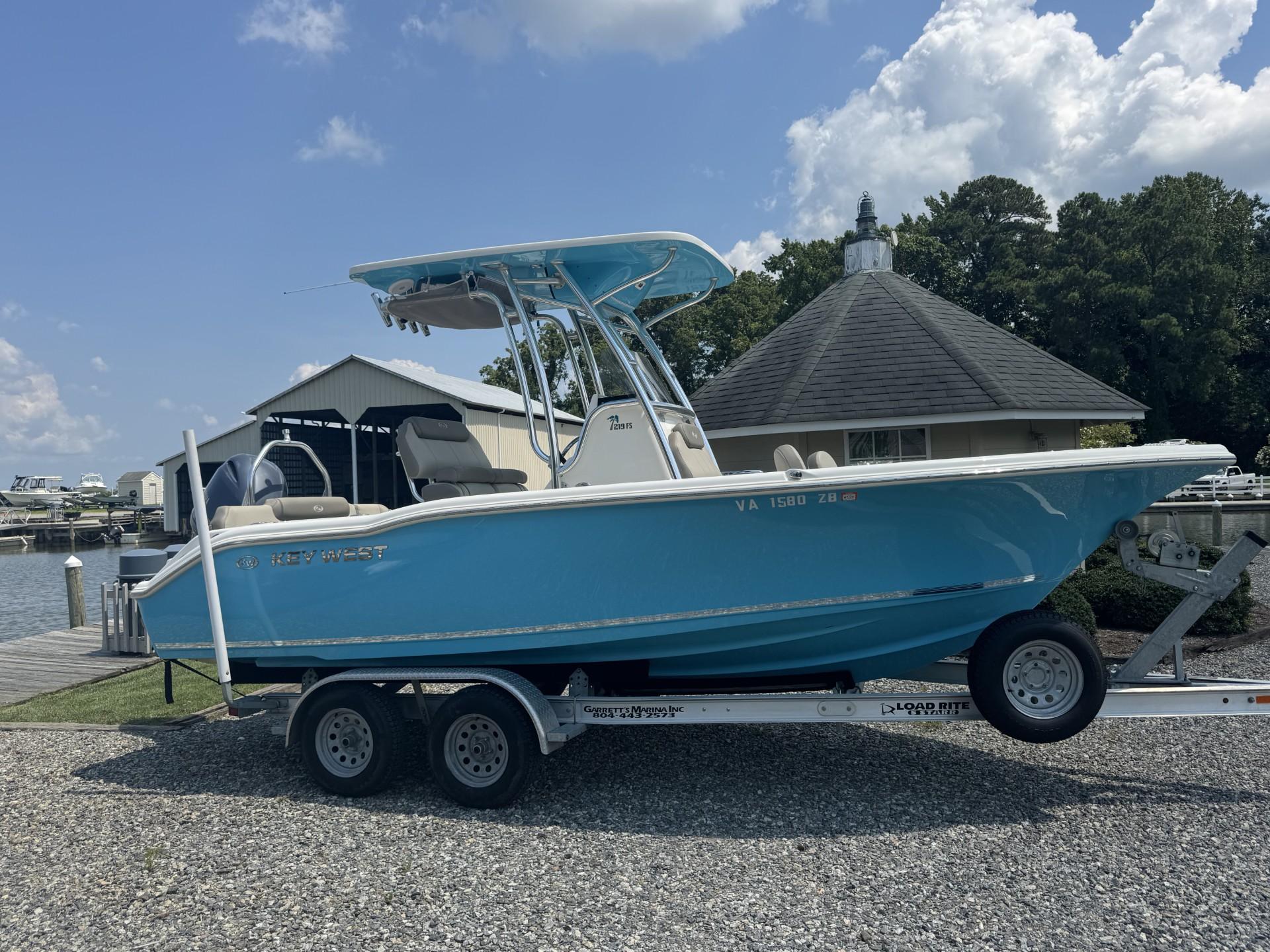 Key West 219 FS 2023 Key West 219 FS boat on trailer, parked near marina under cloudy sky.