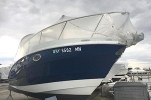 Crownline 264 CR 2018 Crownline 264 CR boat with blue hull, docked and covered, under cloudy sky.