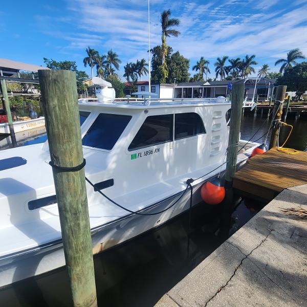 Custom Commercial Express Custom 2018 Commercial Express boat docked by palm trees under blue sky.