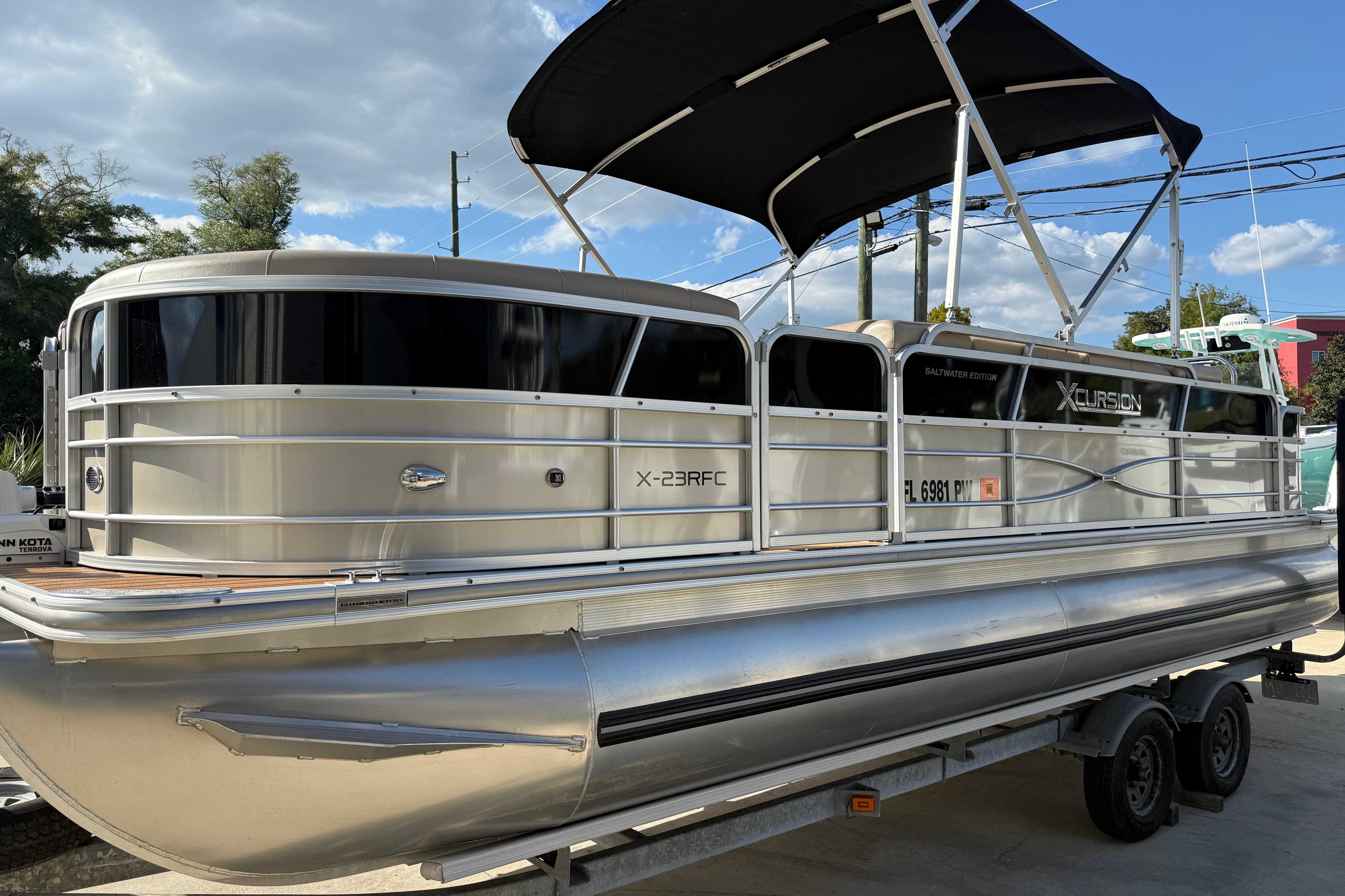 Xcursion 23RFC 2015 Xcursion 23RFC pontoon boat with canopy on trailer, under a clear blue sky.