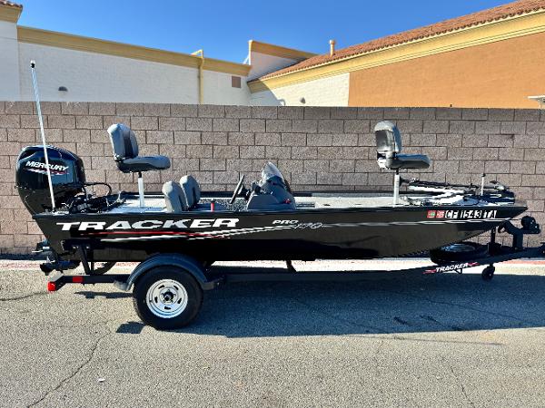 Tracker Pro 170 2024 Tracker Pro 170 boat with Mercury engine, parked on a trailer, against a brick wall.