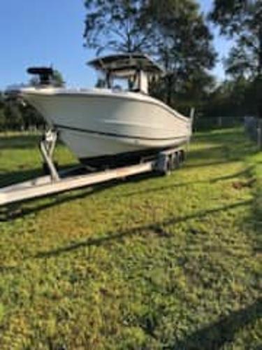 Triton 2690 CC 2004 Triton 2690 CC boat on a trailer in a grassy area.