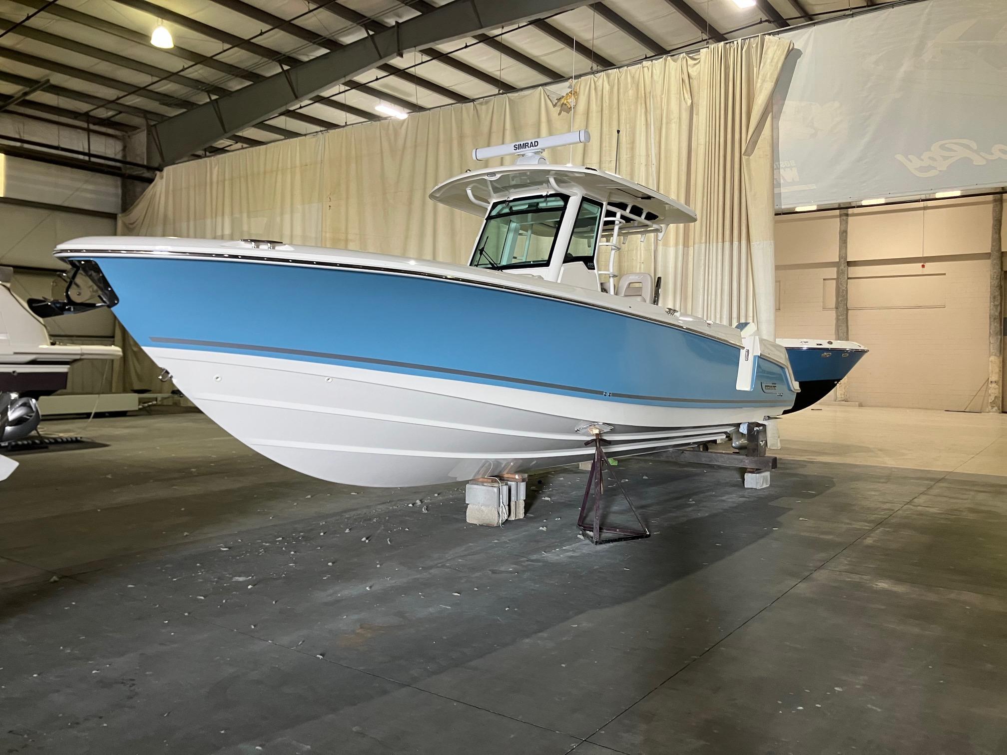 Boston Whaler 330 Outrage 2025 Boston Whaler 330 Outrage boat in a warehouse, featuring a sleek blue and white design.