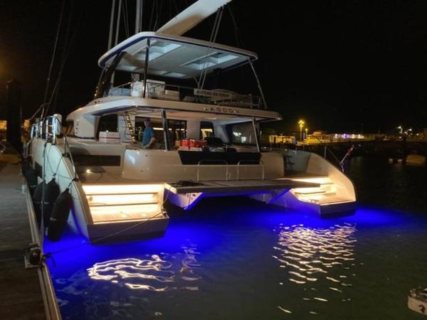 Lagoon SIXTY 5 2024 Lagoon SIXTY 5 catamaran docked at night with blue underwater lights.