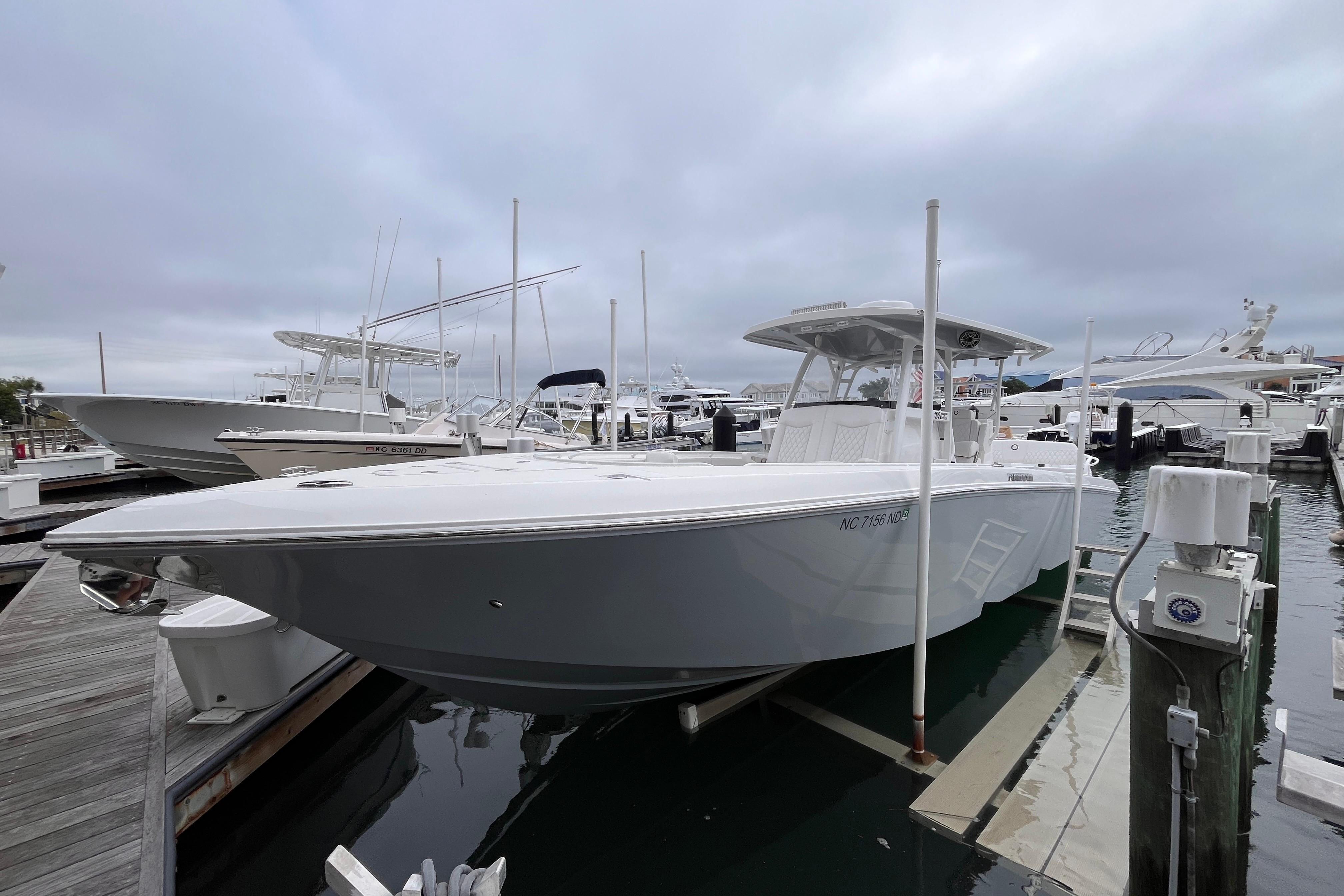 Fountain 34 CC 2025 Fountain 34 CC boat docked at marina under cloudy sky.