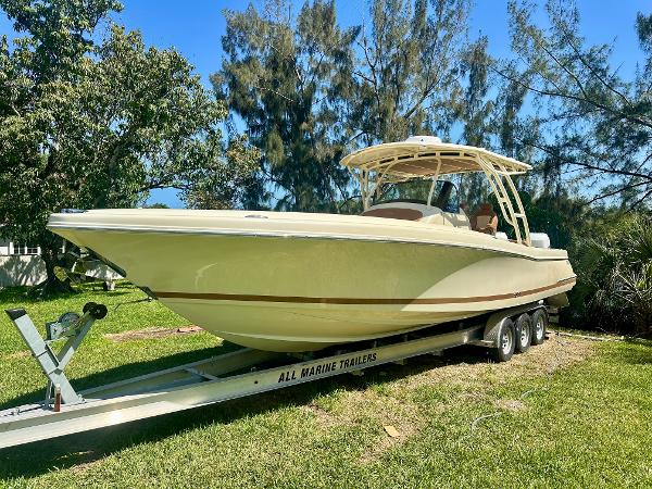 Chris-Craft Catalina 34 2015 Chris-Craft Catalina 34 boat on trailer, parked on grass, surrounded by trees.