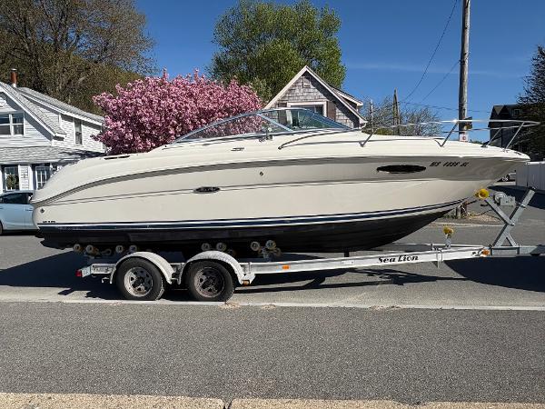Sea Ray 215 Weekender 2007 Sea Ray 215 Weekender boat on trailer, parked on street with blooming tree background.