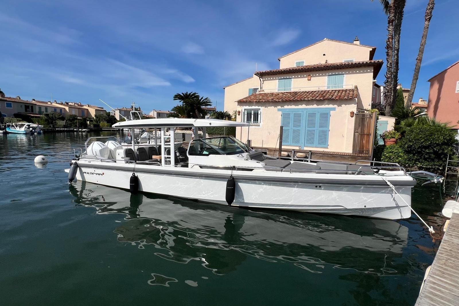Axopar 37 Sun Top 2019 Axopar 37 Sun Top boat docked by waterfront house under clear blue sky.