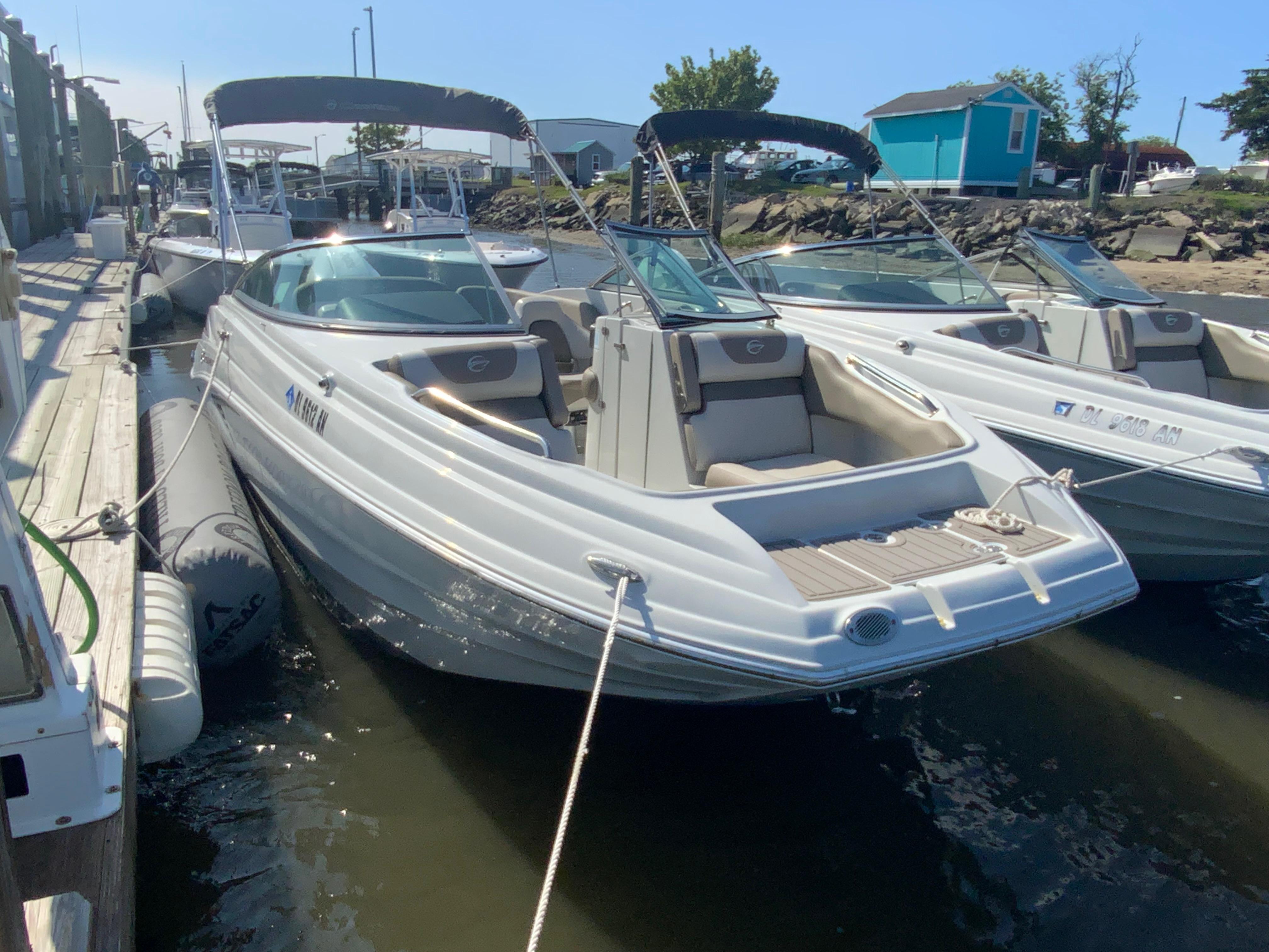 Crownline Eclipse E235 XS 2023 Crownline Eclipse E235 XS boat docked at marina, featuring sleek design and spacious seating.