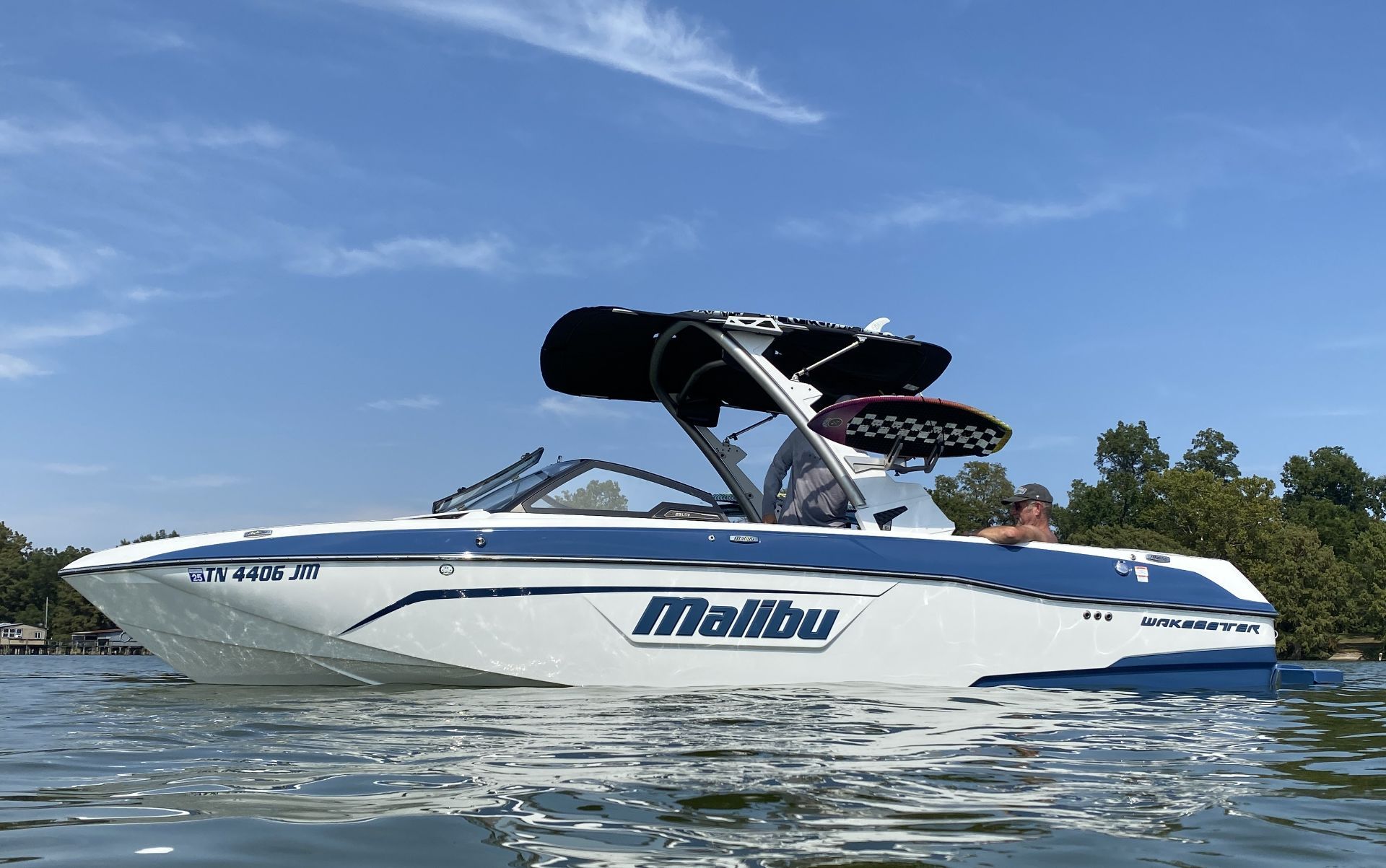 Malibu Wakesetter 23 LSV 2022 Malibu Wakesetter 23 LSV boat on water, clear sky, trees in background.