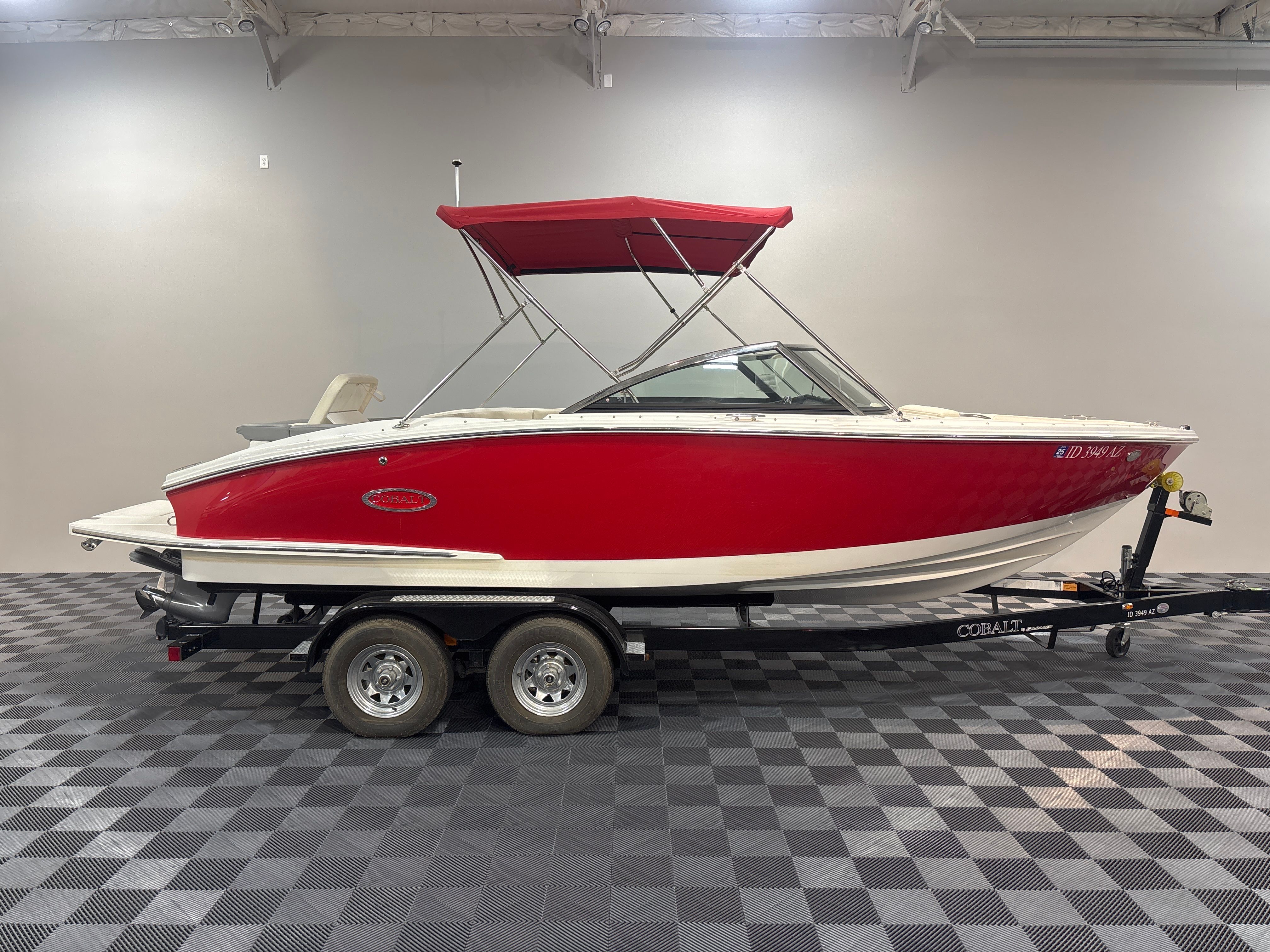 Cobalt CS22 2020 Cobalt CS22 boat with red hull and canopy on trailer in showroom.