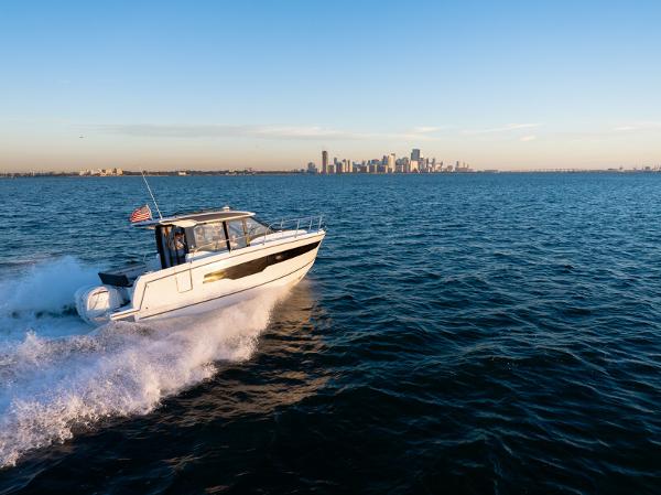 Jeanneau NC 895 2020 Jeanneau NC 895 cruising on open water with city skyline in background.