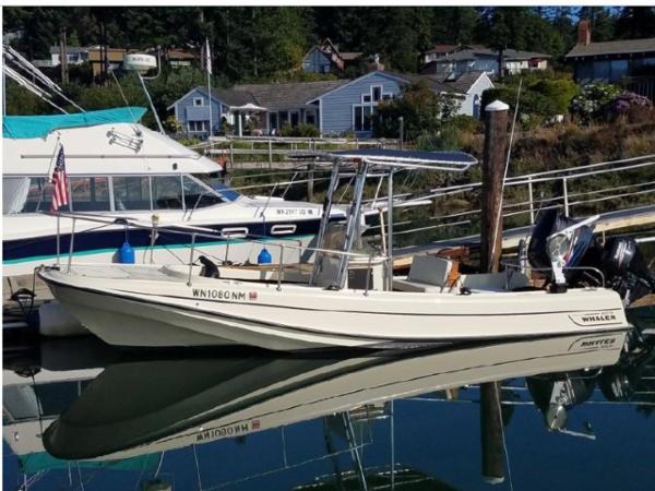 Boston Whaler Outrage 1972 Boston Whaler OUTRAGE boat docked in a marina, reflecting on calm water.